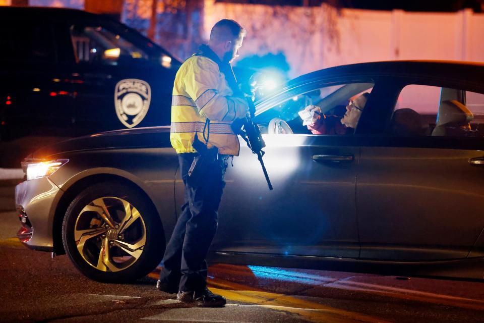 A police officer manning a roadblock talks with an employee of New Hampshire Hospital who was trying to get to work, Friday, Nov. 17, 2023, in Concord, N.H. A shooter killed one person Friday in the lobby of the psychiatric hospital and then was fatally shot by a state trooper, officials said.