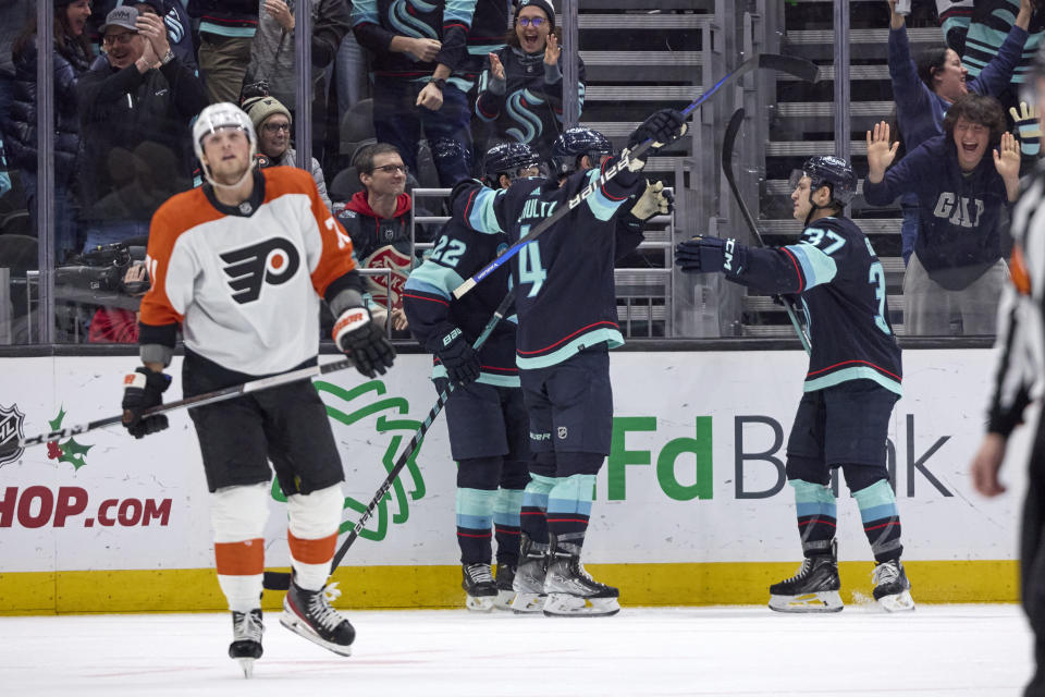 Seattle Kraken defenseman Justin Schultz (4) is congratulated by right wing Oliver Bjorkstrand (22) and center Yanni Gourde (37) after Schultz scored against the Philadelphia Flyers in overtime of an NHL hockey game Friday, Dec. 29, 2023, in Seattle. (AP Photo/John Froschauer)
