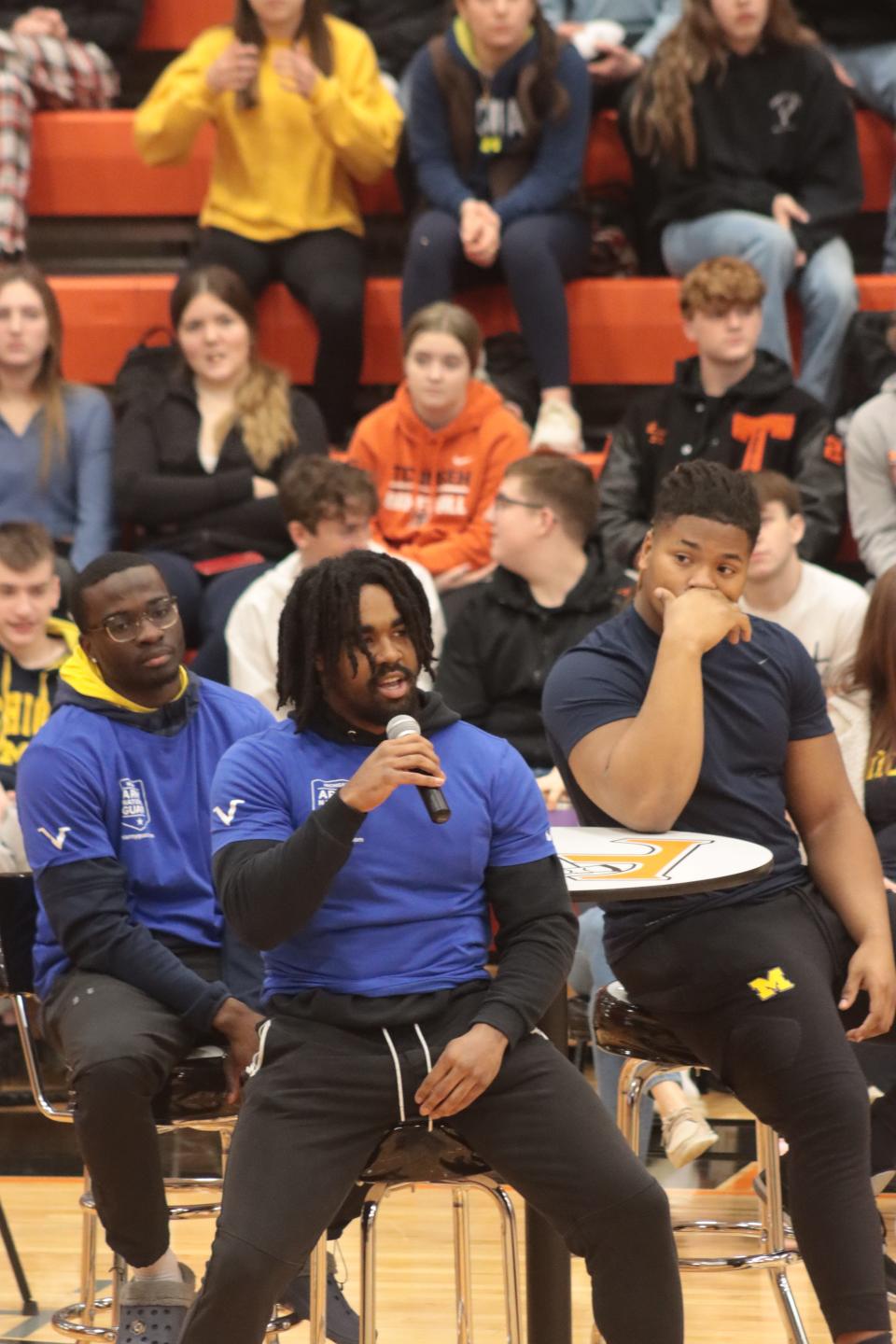 Donovan Edwards, a running back on the University of Michigan football team, answers a question during an assembly Friday, March 24, 2023, at Tecumseh High School with the Michigan Army National Guard and University of Michigan student-athletes. Seated behind Edwards are defensive back Mike Sainristil, left, and defensive lineman Kris Jenkins.