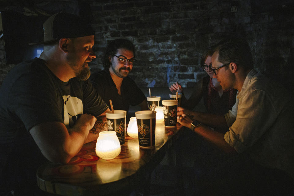 In this June 2019 photo provided by Marvel Comics, left to right, Marvel writer Skottie Young, assistant editors Danny Khazem and Kathleen Wisneski, and executive editor Nick Lowe sit inside the historic Lafitte's Blacksmith Shop in the French Quarter of New Orleans, as they research their upcoming comic book Strange Academy, that is based in New Orleans. (Casey McCauley/Marvel Comics via AP)