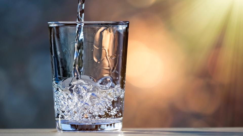 A glass of water on a table being filled up, which can work as a natural treatment for urinary incontinence