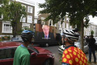 Political campaign group Led By Donkeys transport a screen showing a prerecorded video link of Britain's Boris Johnson delivering a statement, outside the home of his senior aide Dominic Cummings, in London, Sunday May 24, 2020. Several lawmakers from Britain’s governing Conservative Party have joined opposition calls for Johnson’s top aide to be fired for flouting lockdown rules. Dominic Cummings traveled 250 miles (400 kilometers) to his parents’ home with his wife and son as he was coming down with COVID-19 at the end of March. Britain's lockdown, which began March 23, stipulated that people should remain at their primary residence and not visit relatives. (Victoria Jones/PA via AP)