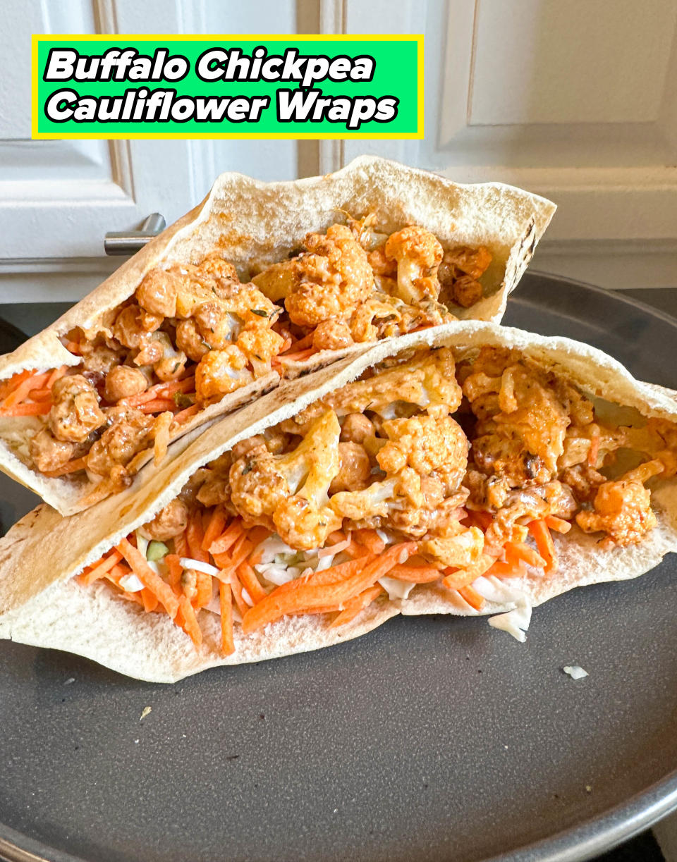 Two pita tacos filled with sautéed cauliflower, carrots, and cabbage, served on a black plate