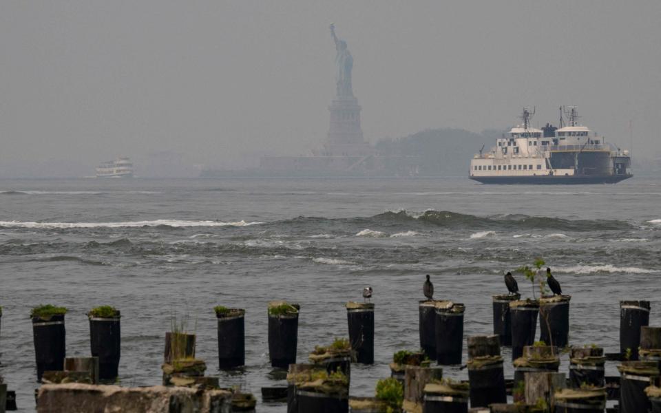 The Statue of Liberty is seen through smoke as wildfires in Canada cause hazy conditions in New York City - ANGELA WEISS