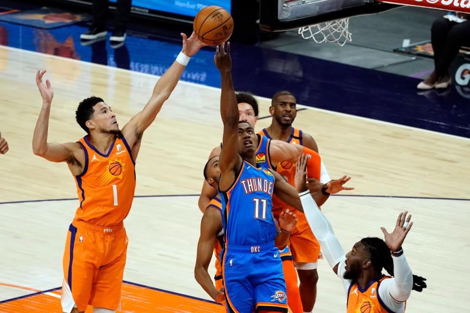 Oklahoma City Thunder guard Theo Maledon (11) drives to the basket past Phoenix Suns guard Devin Booker (1) during the first half of an NBA basketball game on April 2, 2021, in Phoenix.