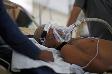 Sitaram Diwakar, 75, a chronic obstructive pulmonary disease (COPD) patient, lies on bed as his family members stand next to him at a hospital in Kanpur, India, May 3, 2018. Picture taken May 3, 2018. REUTERS/Adnan Abidi