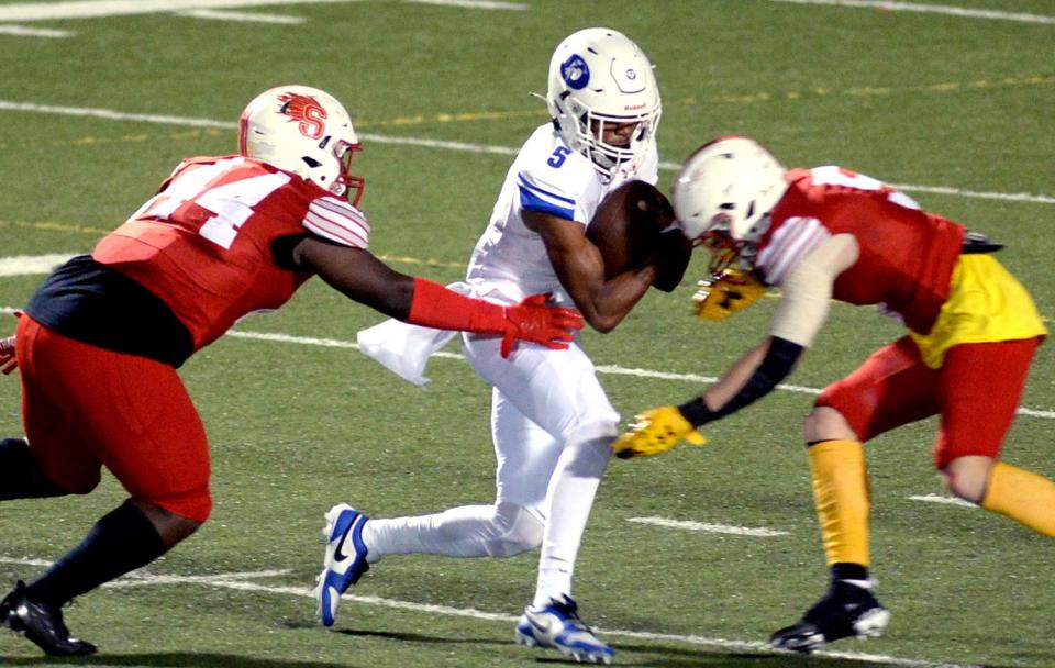 Smyrna's Christopher Kearney (left) and teammate Cole Moyer sandwich Hanseem Cosme of Dover in first half of Smyrna's homecoming game.