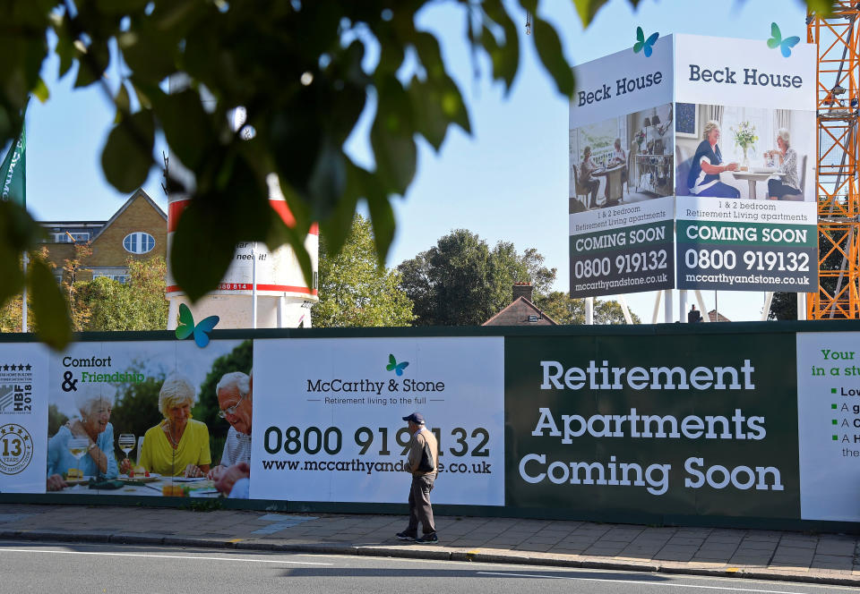 A man walks past hoardings advertising retirement apartments currently being built behind on site by McCarthy & Stone in London, Britain, October 10, 2018. REUTERS/Toby Melville