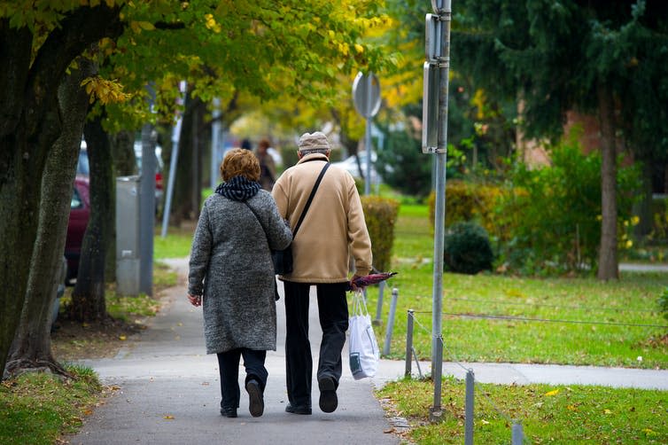 An elderly couple walking down a sidewalk.