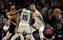 Portland Trail Blazers guard Shaedon Sharpe, left, passes the ball around Sacramento Kings guard Davion Mitchell, center, and forward Domantas Sabonis, right, during the first half of an NBA basketball game in Portland, Ore., Friday, March 31, 2023. (AP Photo/Steve Dykes)