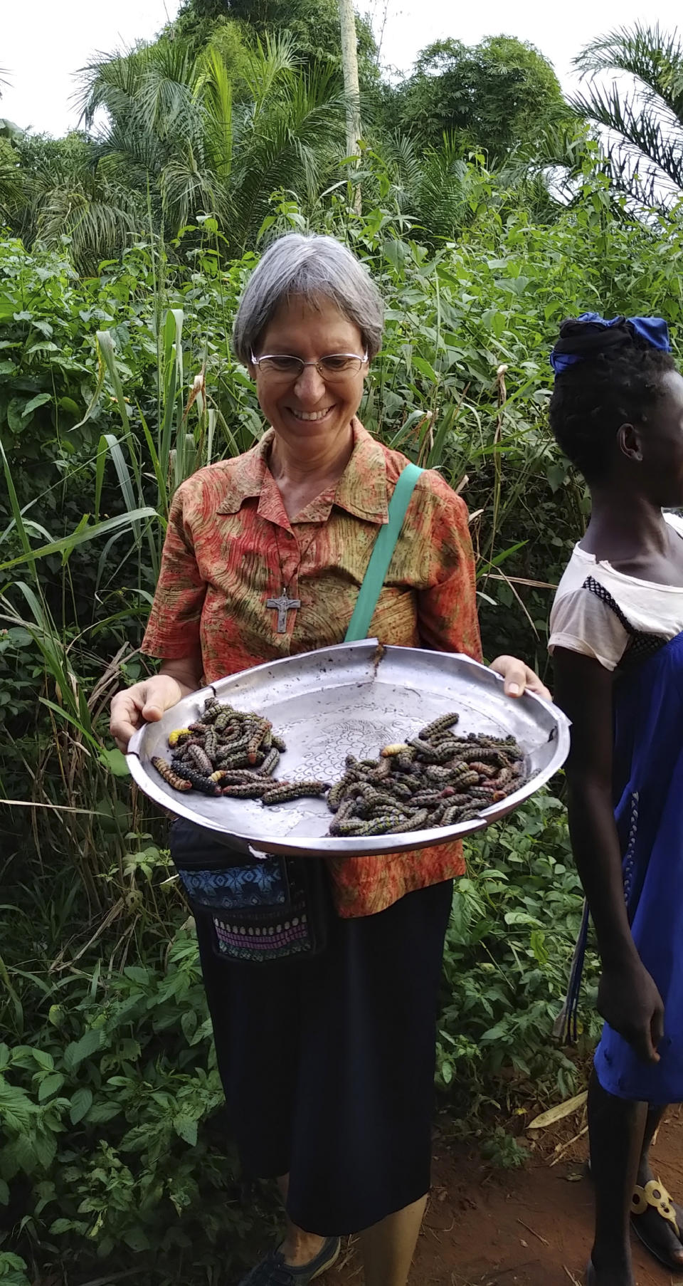 In this July 28, 2020, photo provided by Sister Luzia Premoli, she holds a makongo, a wooden bowl, near a market in Bagandou in the Central African Republic. Premoli was the first woman appointed to a Vatican congregation in the history of the Catholic Church. She is currently located in Africa where she teaches young women about the Bible and Christianity and works with a community of Pygmies on education and agricultural initiatives in the equatorial forest. (Sister Luzia Premoli via AP)