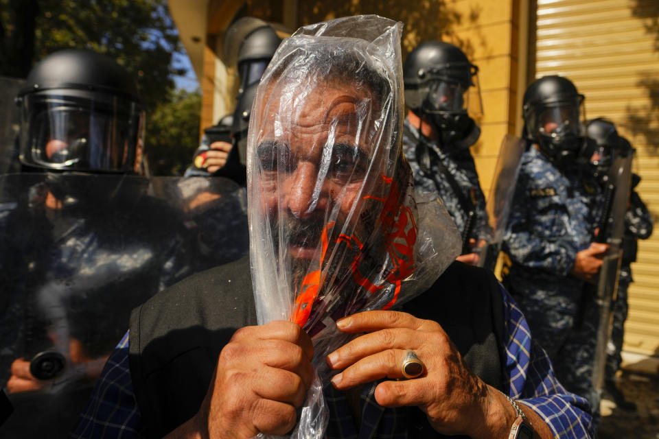 A retired member of Lebanese security forces uses a plastic bag to protect himself from tear gas during clashes with the Lebanese army and riot police during a protest in Beirut, Lebanon, Tuesday, April 18, 2023. AP Photo/Hassan Ammar)