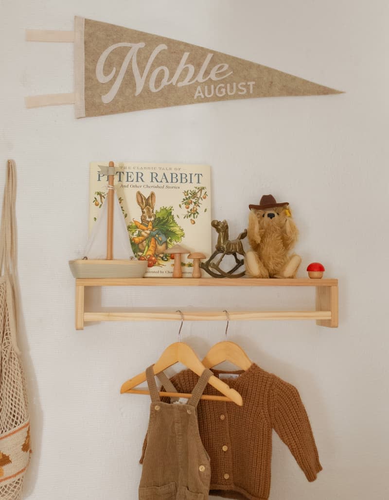 small floating shelf with decor objects, and rod for hanging baby clothes