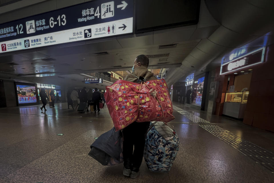 A migrant worker wearing a face mask carries his belonging as he arrived at the West Railway Station in Beijing, Friday, Jan. 6, 2023. China is seeking to minimize the possibility of a major new COVID-19 outbreak during this month's Lunar New Year travel rush following the end of most pandemic containment measures. (AP Photo/Wayne Zhang)