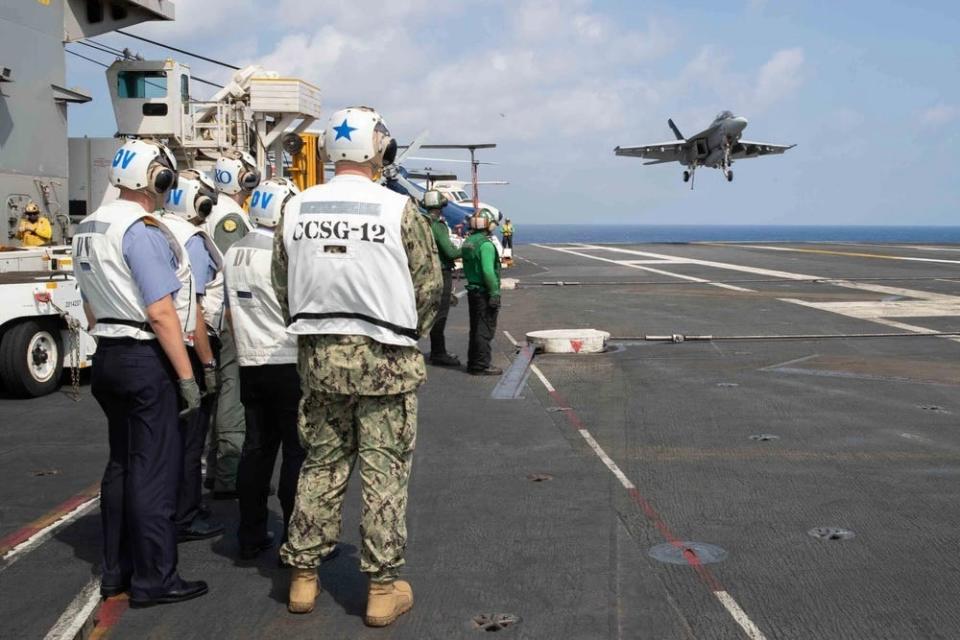 US and Turkish naval leaders observe a military aircraft during takeoff from the flight deck of an aircraft carrier