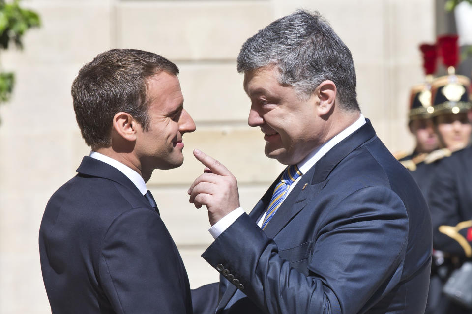 FILE - Ukrainian President Petro Poroshenko, right, gestures speaking to French President Emmanuel Macron at the Elysee Palace, in Paris, June 26, 2017. A peace agreement for eastern Ukraine has remained stalled for years, but it has come into the spotlight again amid a Russian military buildup near Ukraine that has fueled invasion fears. On Thursday, Feb. 10, 2022 presidential advisers from Russia, Ukraine, France and Germany are set to meet in Berlin to discuss ways of implementing the deal that was signed in the Belarusian capital of Minsk in 2015. (AP Photo/Michel Euler, File)