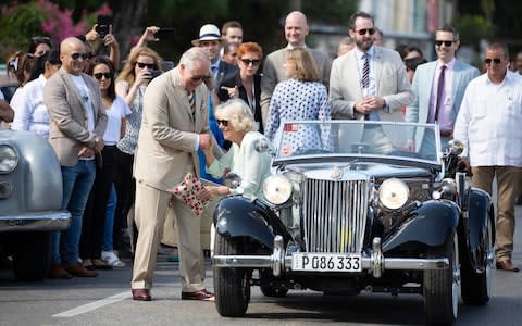 The Prince helps his wife out of the classic MG roadster - Credit: PA