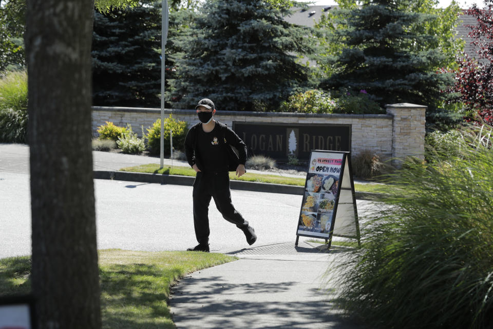 Zhen Yi, who operates the YS Street Food food truck, walks back to his truck after setting up a sign, Monday, Aug. 10, 2020, near the suburb of Lynnwood, Wash., north of Seattle. Long seen as a feature of city living, food trucks are now finding customers in the suburbs during the coronavirus pandemic as people are working and spending most of their time at home. (AP Photo/Ted S. Warren)