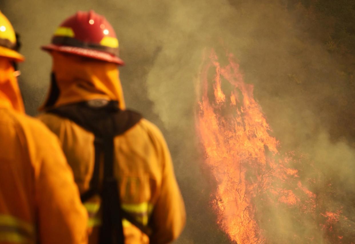 Firefighters keep an eye on flames as pockets of unburned vegetation flare in the California wildfires: Mike Eliason/Santa Barbara County Fire Department via AP