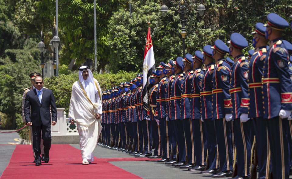 In this photo made available by Qatar News Agency, QNA, Qatari Emir Tamim bin Hamad Al Thani, and Egyptian President Abdel-Fattah el-Sissi, review an honor guard at the presidential palace in Cairo, Egypt, Saturday, June 25, 2022. Qatar's emir arrived in Cairo to hold talks with Egypt's president in his first visit since the two countries agreed to reset relations after more than seven years of diplomatic animosity. (QNA via AP)