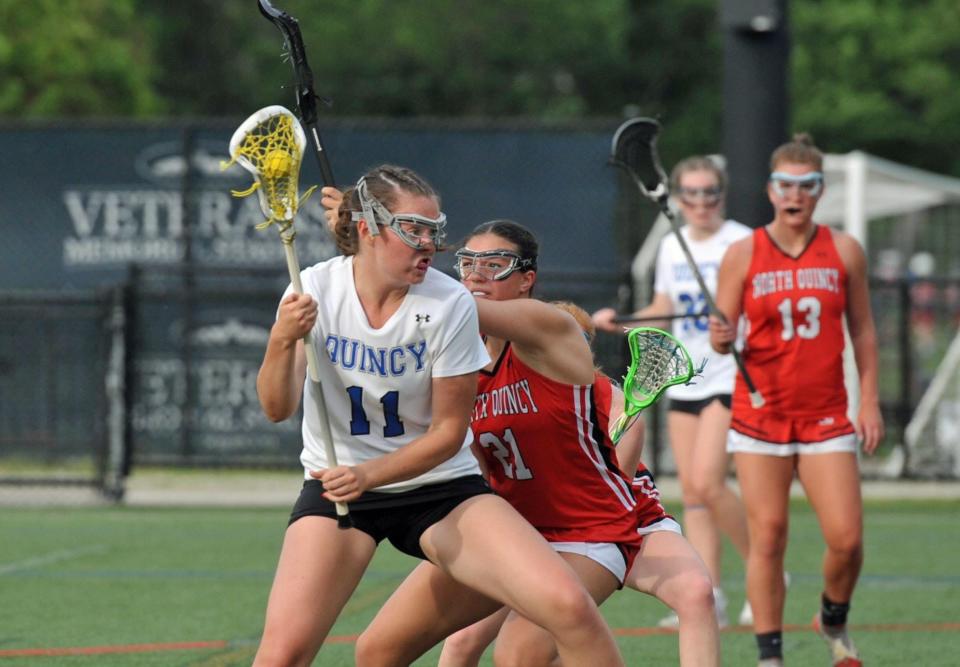 North Quincy's Autumn O'Campos, right, tries to knock the ball from Quincy's Delia Nichol, left, during girls lacrosse at Veterans Stadium in Quincy, Tuesday, May 16, 2023.