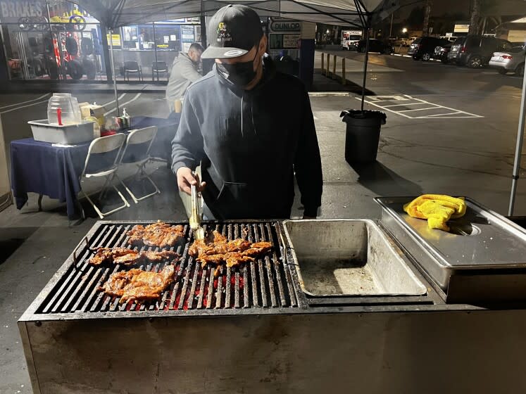 Hector "Guero" Garcia grills carne asada over a charcoal grill at Taqueria El Puerto in Anaheim.