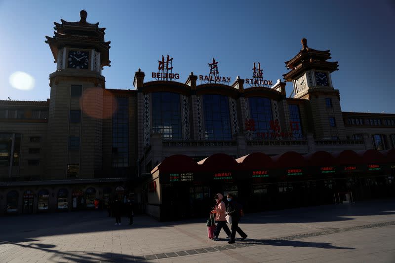 Travelers wearing face masks following the coronavirus disease (COVID-19) outbreak walk outside a railway station in Beijing