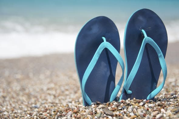 Pair of blue flip flops on sand beach