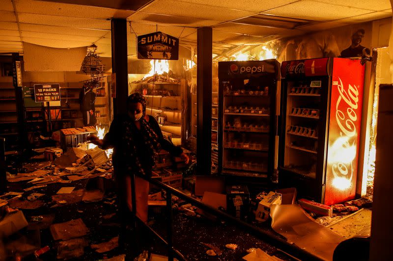 A woman reacts while protesters set fire in a liquor store as demonstrations continue in Minneapolis