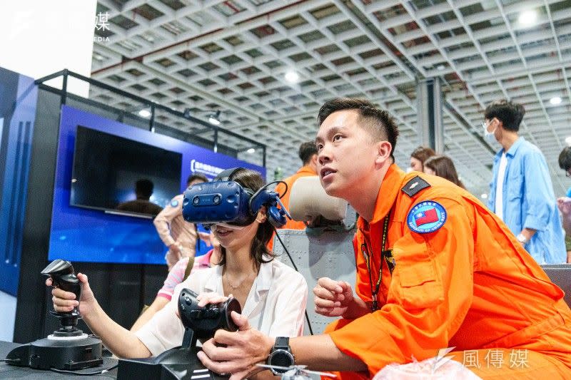 <cite>海軍反潛直升機飛行官帶領民眾運用VR技術體驗飛行訓練。（傅啟禎攝）</cite>