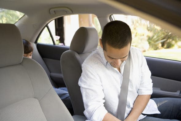 Man buckling seat belt in car