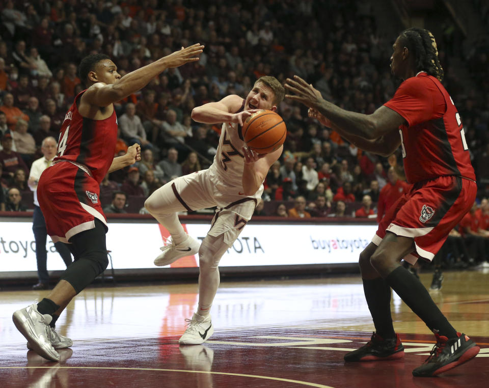 Virginia Tech's Sean Pedulla (3) center, drives toward the basket while defended by North Carolina State's Casey Morsell (14) and Greg Gantt (23) during the second half of an NCAA college basketball game Saturday, Jan. 7, 2023, in Blacksburg, Va. (Matt Gentry/The Roanoke Times via AP)