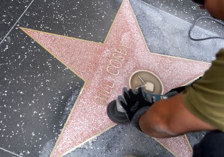 A worker cleans graffiti on actor Bill Cosby's star on the Hollywood Walk of Fame in Los Angeles December 5, 2014. REUTERS/Phil McCarten