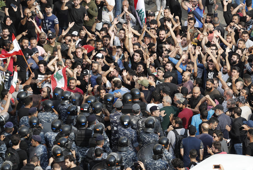 Hezbollah supporters stand in front of Lebanese riot policemen, as they shout slogans pro-Hezbollah leader Sayyed Hassan Nassrallah, during a protest near the government palace, in downtown Beirut, Lebanon, Friday, Oct. 25, 2019. Hundreds of Lebanese protesters set up tents, blocking traffic in main thoroughfares and sleeping in public squares on Friday to enforce a civil disobedience campaign and keep up the pressure on the government to step down. (AP Photo/Hussein Malla)