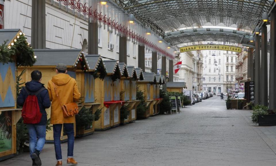 People walk through a closed Christmas market n Vienna, Austria