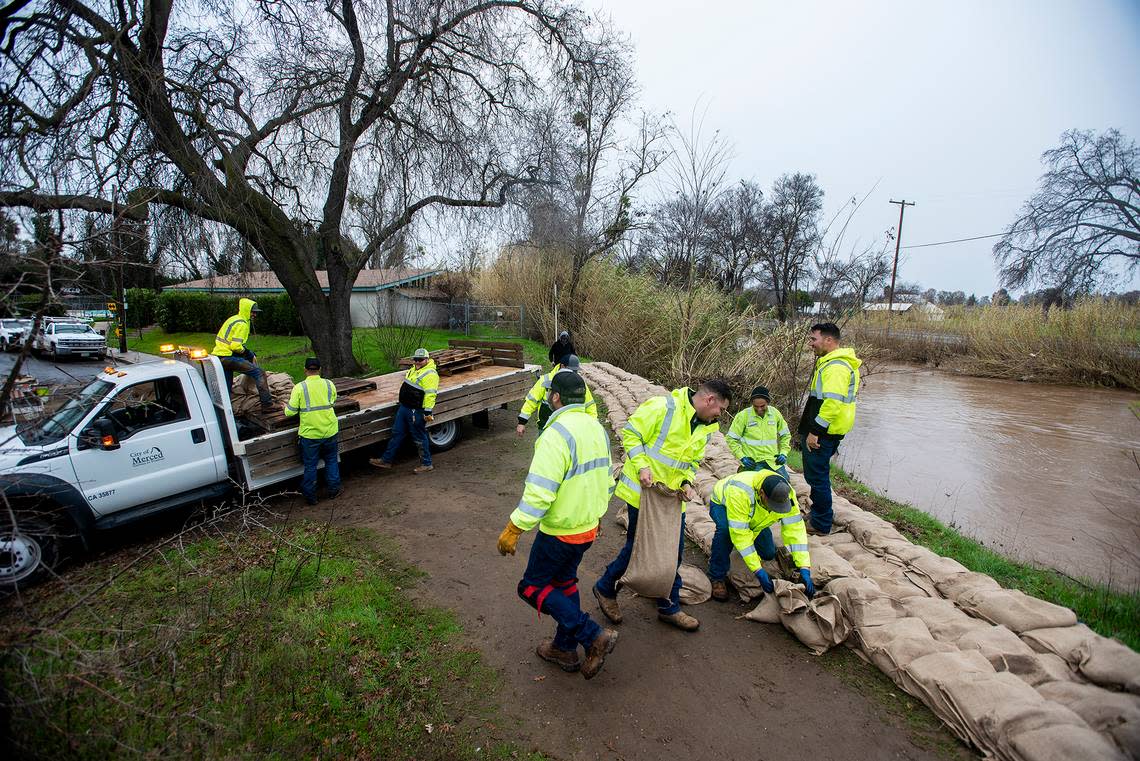 City of Merced Public Works employees construct a sandbag wall along Bear Creek near the intersection of W Street and West 23rd Street in Merced, Calif., on Wednesday, Jan. 11, 2023.