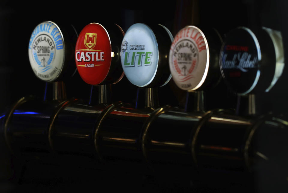 Beer taps of South African Brewery brands, Castle, Castle Light and Black Label, are seen through the window of a closed bar in Cape Town, South Africa, Thursday, May 7, 2020. South African Breweries, the second biggest brewer in the world, says it may have to destroy 400 million bottles of the beer because of the country's ban on alcohol sales during its lockdown to combat the spread of the coronavirus. (AP Photo/Nardus Engelbrecht)