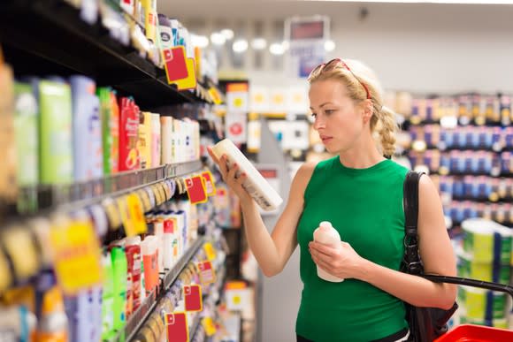 A woman looking at a consumer product at a supermarket.