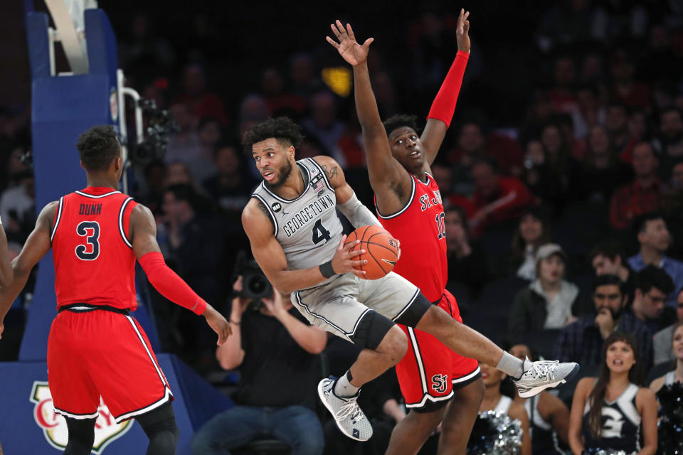 Georgetown guard Jagan Mosely (4) leaps to pass with St. John's forward Marcellus Earlington (10) defending and St. John's guard Rasheem Dunn (3) watching during the second half of an NCAA college basketball game in the first round of the Big East men's tournament Wednesday, March 11, 2020, in New York. (AP Photo/Kathy Willens)