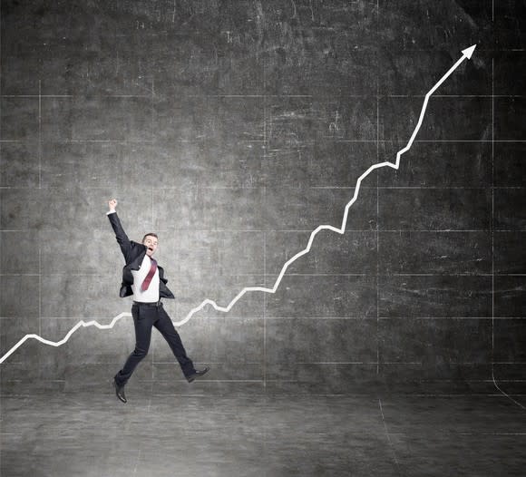 A businessman celebrating in front of a stock chart moving upwards