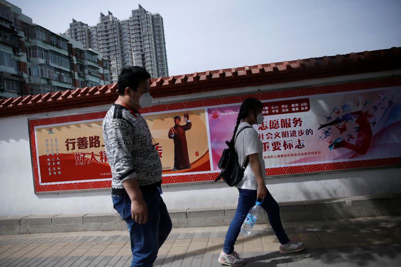 Zhang Jianpeng and his wife Zhang Ruirui wearing face masks walk on a street as they look for jobs in Beijing