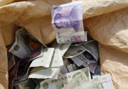 Chinese Yuan bank notes are seen in a vendor's cash sack at a market in Beijing