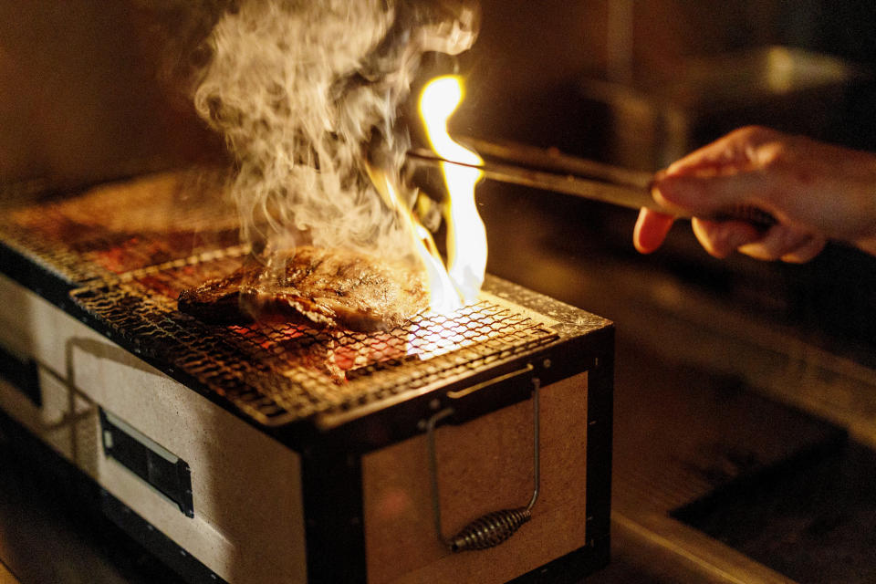 A chef cooks a steak on a Japanese barbecue at Brasserie Surrealiste in Brussels, Wednesday, Sept. 28, 2022. A group of restaurant owners in Brussels has imagined how a future without gas and electricity would look like for gourmets. Dinner guests, served at the Brasserie Surrealiste and cooked by Racines restaurant employees, were the first to experience it: No ovens, no stoves, no hot plates, no coffee machines and no light bulbs. (AP Photo/Olivier Matthys)