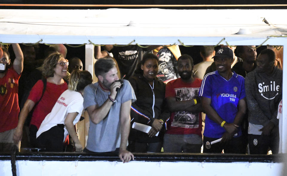 Migrants stand on the Open Arms rescue ship before disembarking on the Sicilian island of Lampedusa, southern Italy, Tuesday, Aug. 20, 2019. Italian prosecutor Luigi Patronaggio has ordered the seizure of a migrant rescue ship and the immediate evacuation of more than 80 migrants remaining on board, capping dramatic developments that saw 15 migrants jump into the sea in a desperate bid to reach land and the Spanish government dispatch a Naval ship on a long journey to resolve the escalating crisis. (AP Photo/Salvatore Cavalli)