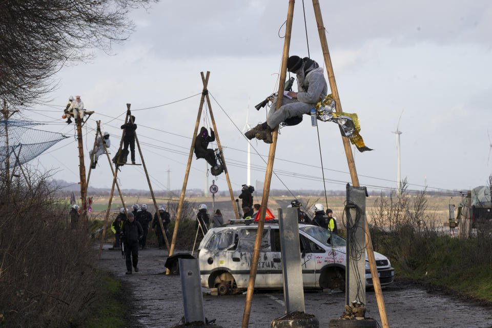 Climate activists sit in so-called tripos and block a road at the village Luetzerath near Erkelenz, Germany, Wednesday, Jan. 11, 2023. Police have entered the condemned village in launching an effort to evict activists holed up at the site in an effort to prevent its demolition to make way for the expansion of a coal mine. (AP Photo/Michael Probst)