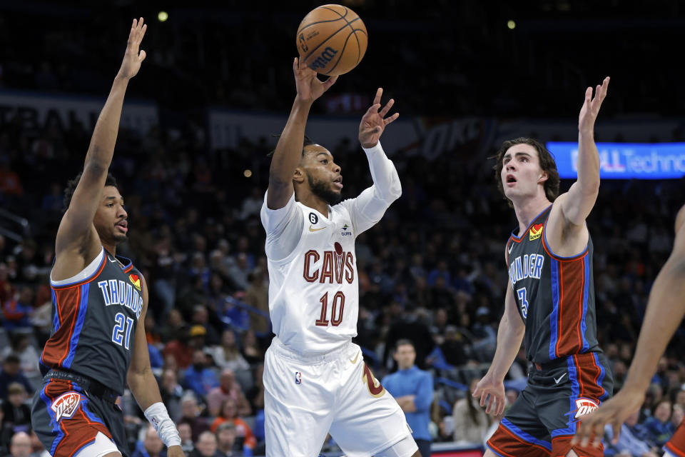 Cleveland Cavaliers guard Darius Garland, middle, passes the ball from between Oklahoma City Thunder guards Aaron Wiggins, left, and Josh Giddey during the first half of an NBA basketball game Friday, Jan. 27, 2023, in Oklahoma City. (AP Photo/Nate Billings)