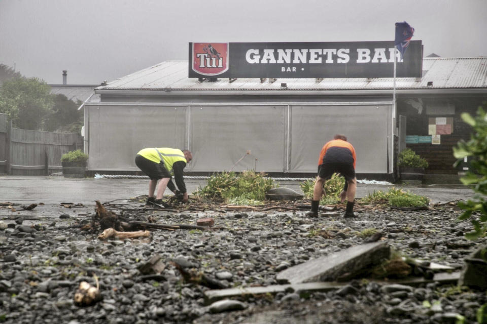 Men clear debris by hand on a flooded road in Te Awanga, southeast of Auckland, New Zealand, Tuesday, Feb. 14, 2023. The New Zealand government declared a state of emergency across the country's North Island, which has been battered by Cyclone Gabrielle. (Warren Buckland/Hawkes Bay Today via AP)
