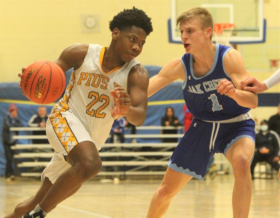 Pius XI's Jaquan Johnson (22) drives to the basket against Oak Creek's Marty Kleppek (1) on Tuesday Dec. 28, 2021 at Concordia University's Buuck Field House.