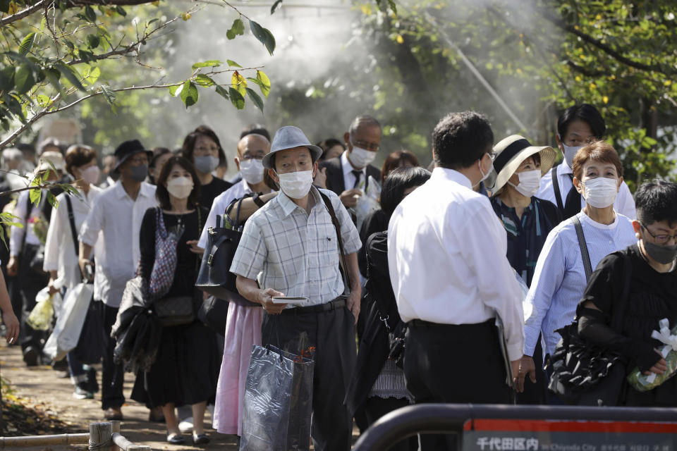 People wait in lines to lay flowers and pay respects to former Japanese Prime Minister Shinzo Abe at the stands set up outside the venue for his state funeral in Tokyo Tuesday, Sept. 27, 2022. (Kyodo News via AP)