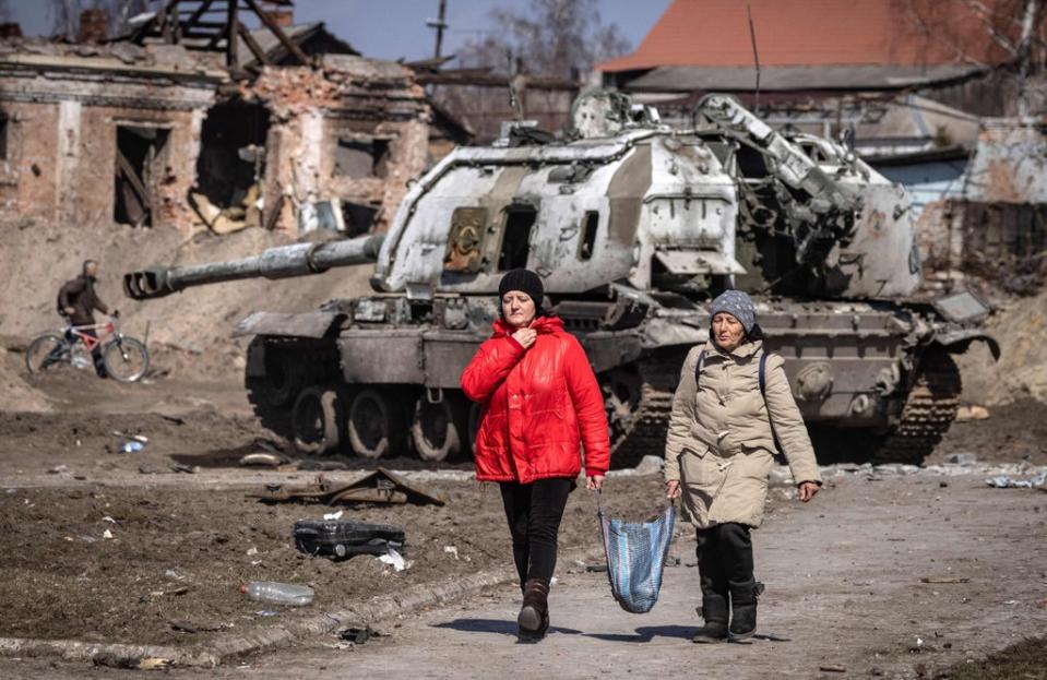 Residents walk past a damaged Russian tank in the northeastern city of Trostianets (AFP via Getty Images)